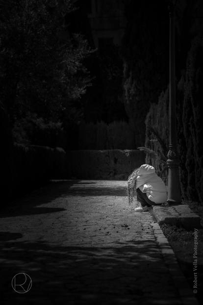 A narrow alley at night, a dog sitting in the one patch of light